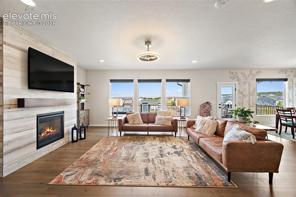 Image 10 of 47: Spacious living area featuring wood-finish flooring, a contemporary firepla