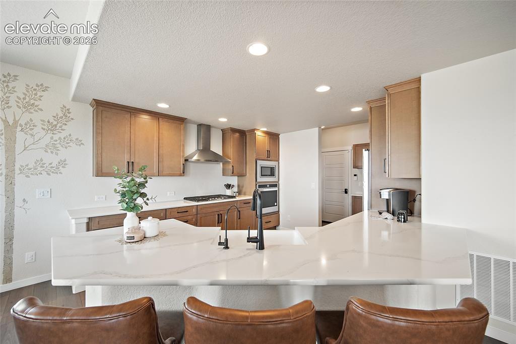 Image 15 of 47: Kitchen featuring light wood cabinetry, recessed lighting, stainless steel