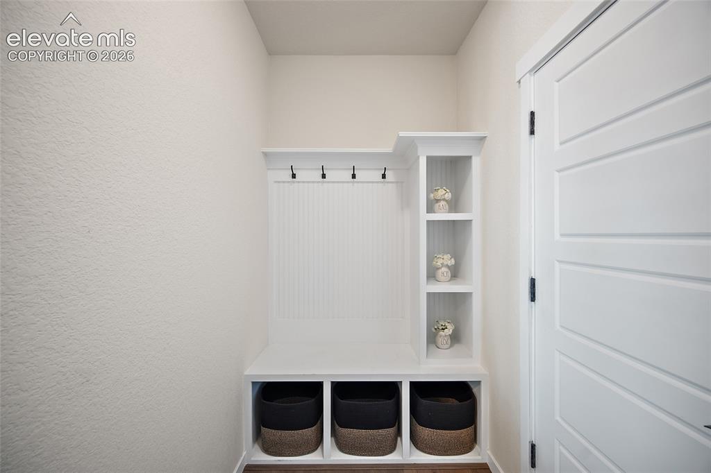 Image 18 of 47: Built-in white storage unit with cubbies, upper shelving, and dark-finish c