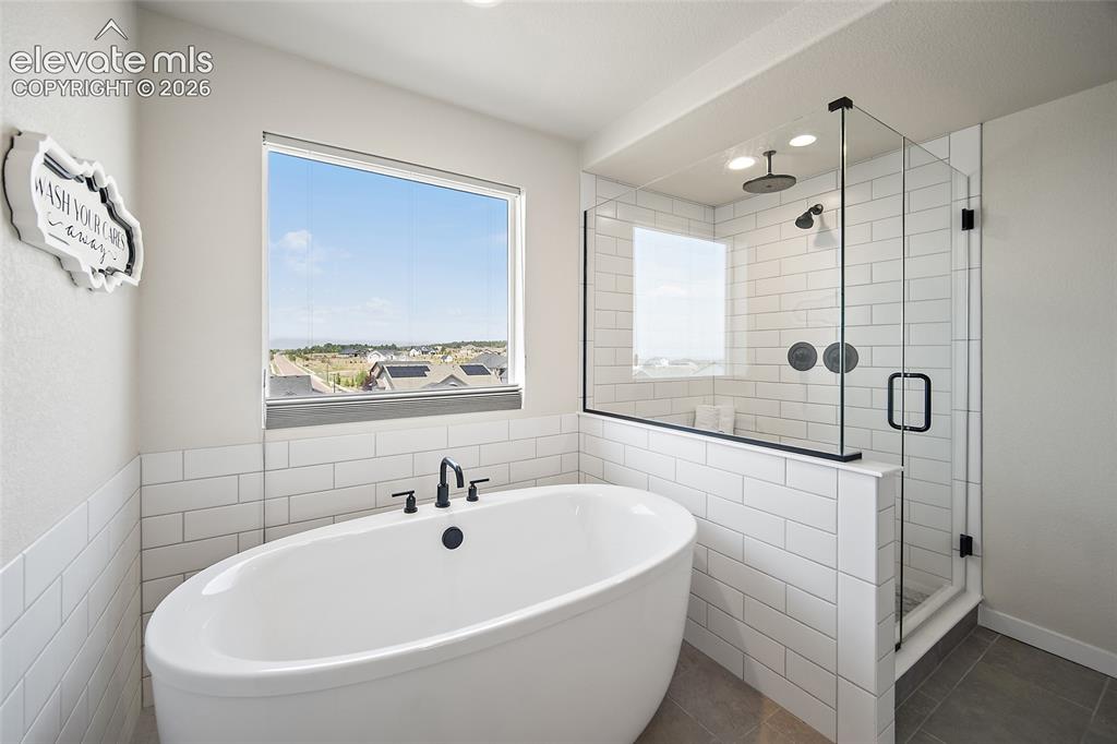 Image 20 of 47: Freestanding soaking tub with matte black fixtures, glass-enclosed shower w