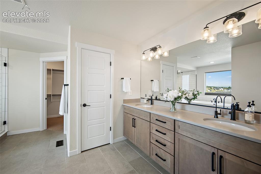 Image 21 of 47: Dual vanity with stone-finish countertops, matte black fixtures, full-width