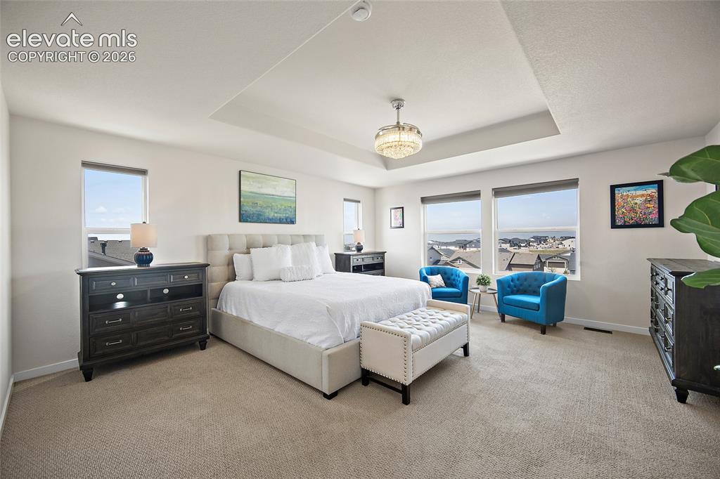 Image 22 of 47: Recessed ceiling with a central chandelier, multiple windows, and light-ton