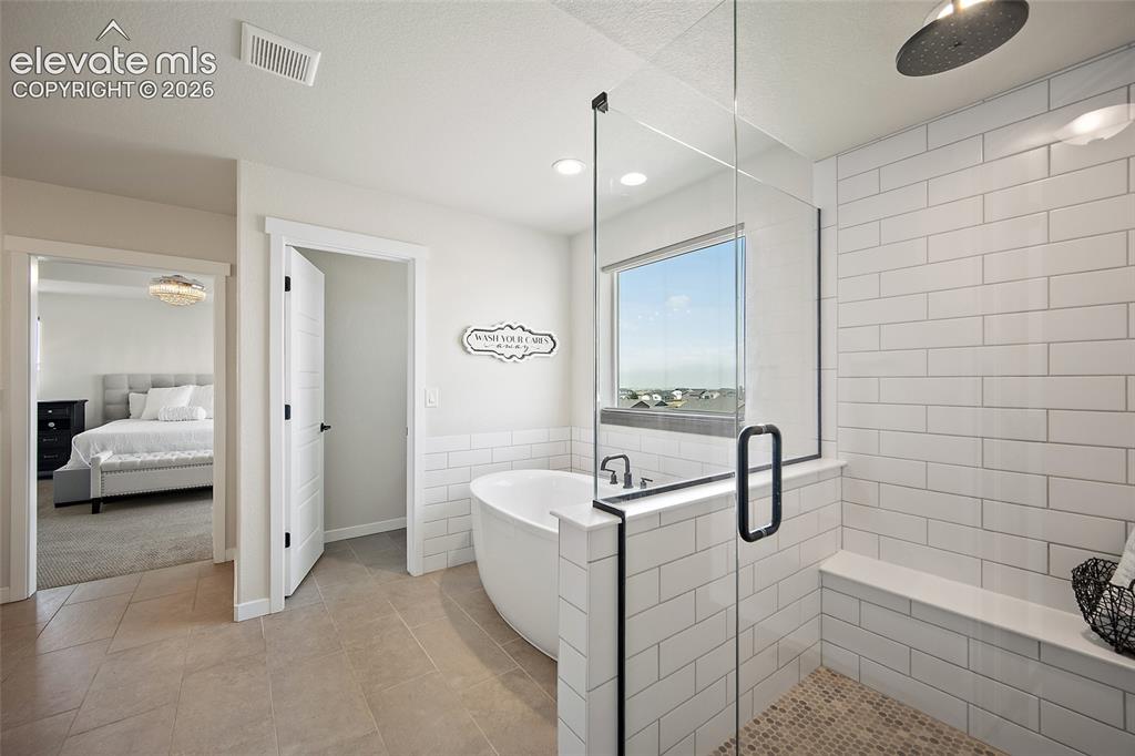 Image 23 of 47: Freestanding soaking tub, glass-enclosed shower with subway tile surround,