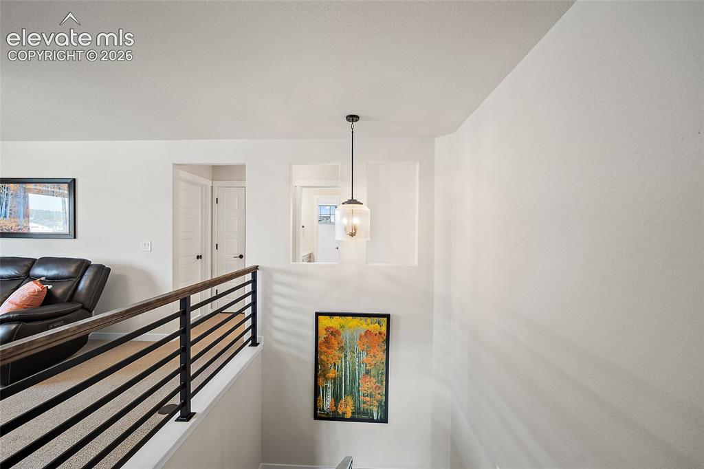 Image 28 of 47: Contemporary wood-finish handrail with black metal balusters, overhead pend