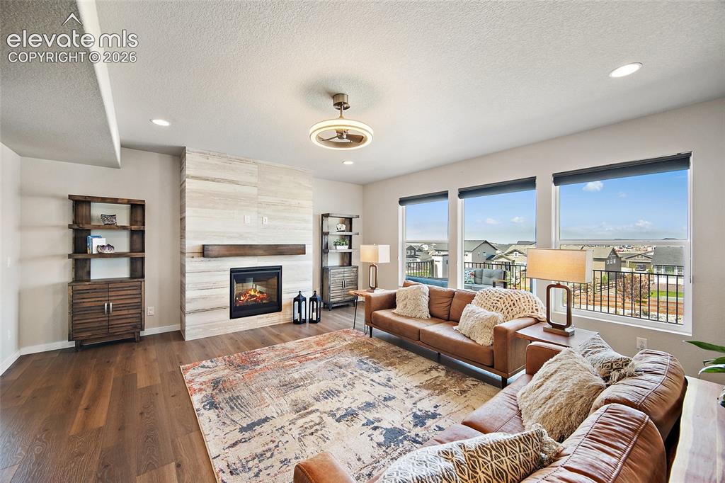 Image 3 of 47: Wood-finish flooring, recessed lighting, and a fireplace with a wood mantel