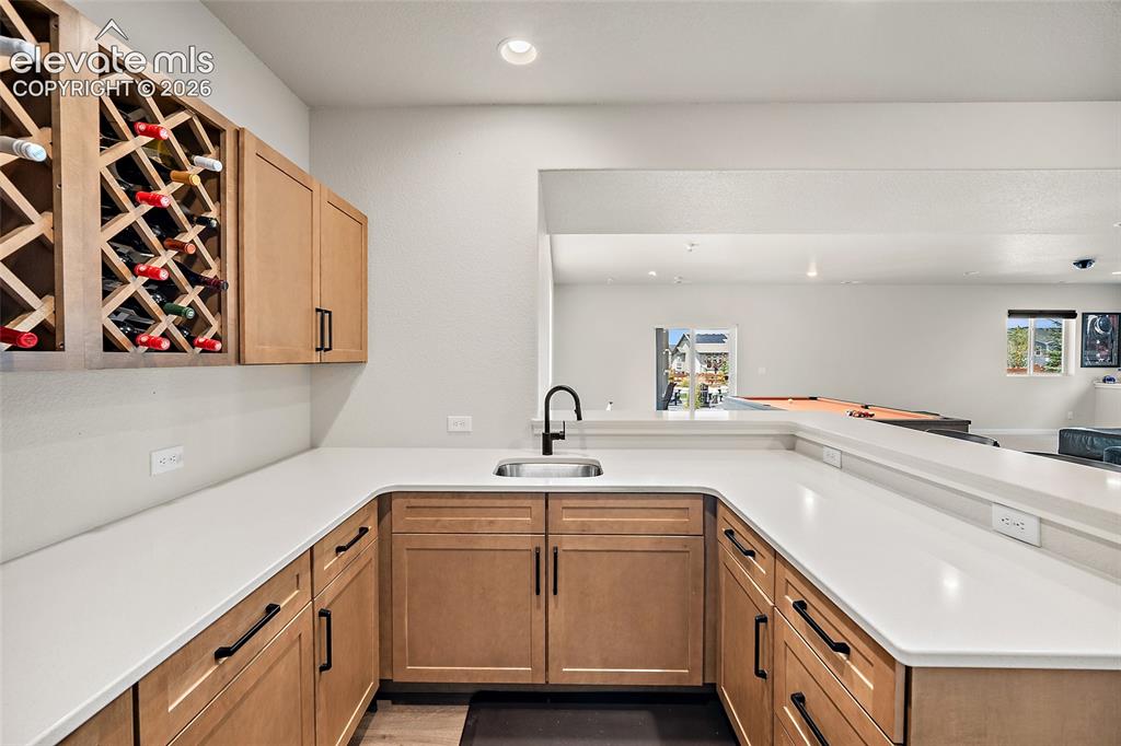Image 33 of 47: Wet bar featuring, built-in wine storage, a stainless steel sink with a mat