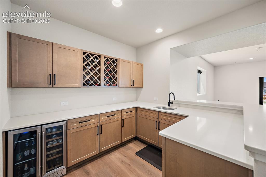 Image 34 of 47: Built-in wet bar with solid surface countertops, a stainless steel wine ref