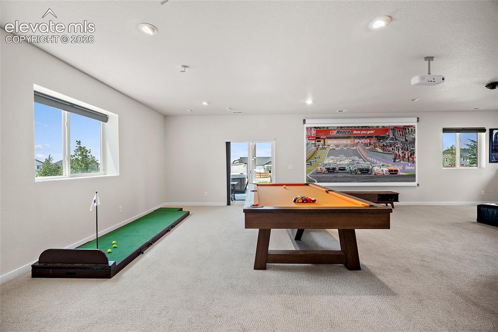 Image 42 of 47: Spacious entertainment room featuring recessed lighting, projector, screen,