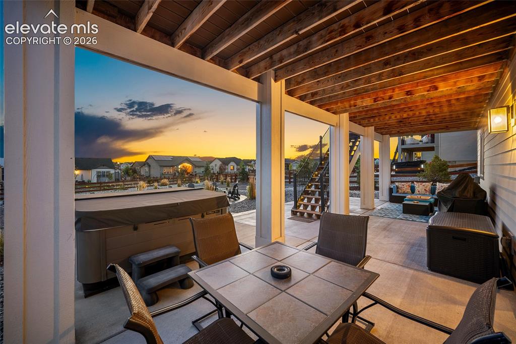 Image 45 of 47: Covered patio featuring exposed wood beam ceiling, concrete flooring, and e