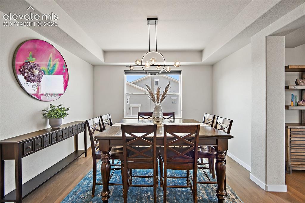 Image 9 of 47: Tray ceiling with a contemporary chandelier, wood-finish flooring, and buil