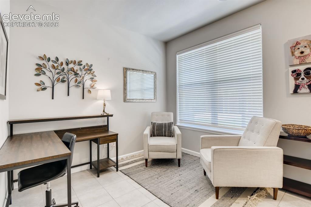 Image 21 of 23: Bright room featuring tile flooring, a large window with blinds, and light-