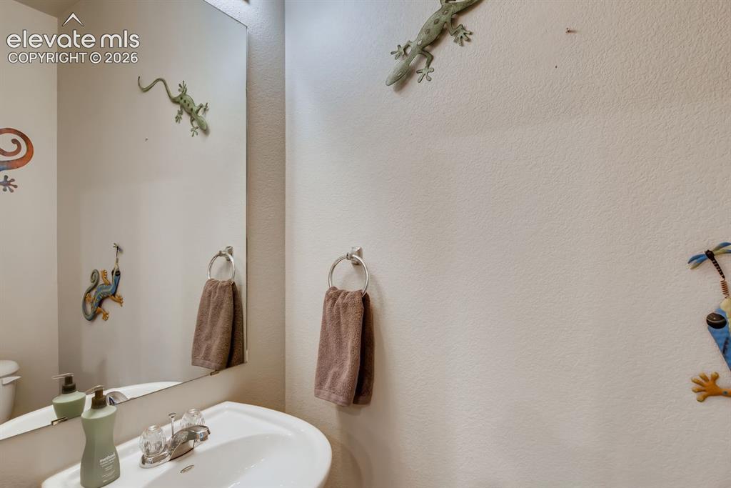 Image 23 of 23: Pedestal sink with chrome faucet, large wall mirror, and neutral wall tones