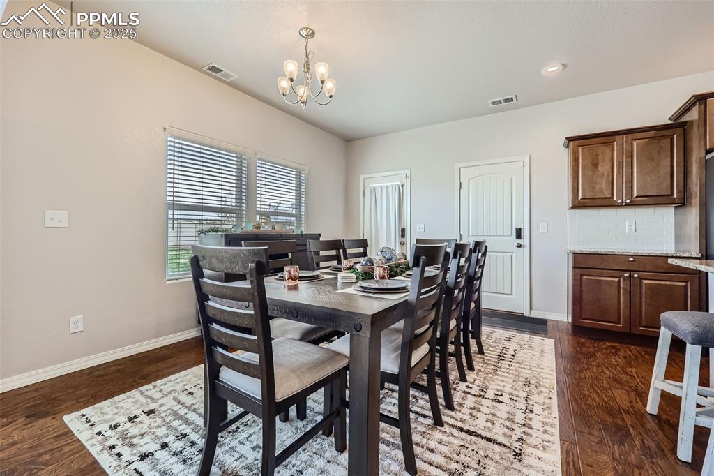 Image 11 of 29: Dining space with a chandelier, baseboards, and dark wood finished floors