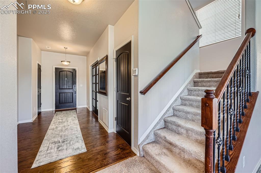 Image 14 of 29: Entrance foyer with dark wood-style flooring, stairs, baseboards, and a tex
