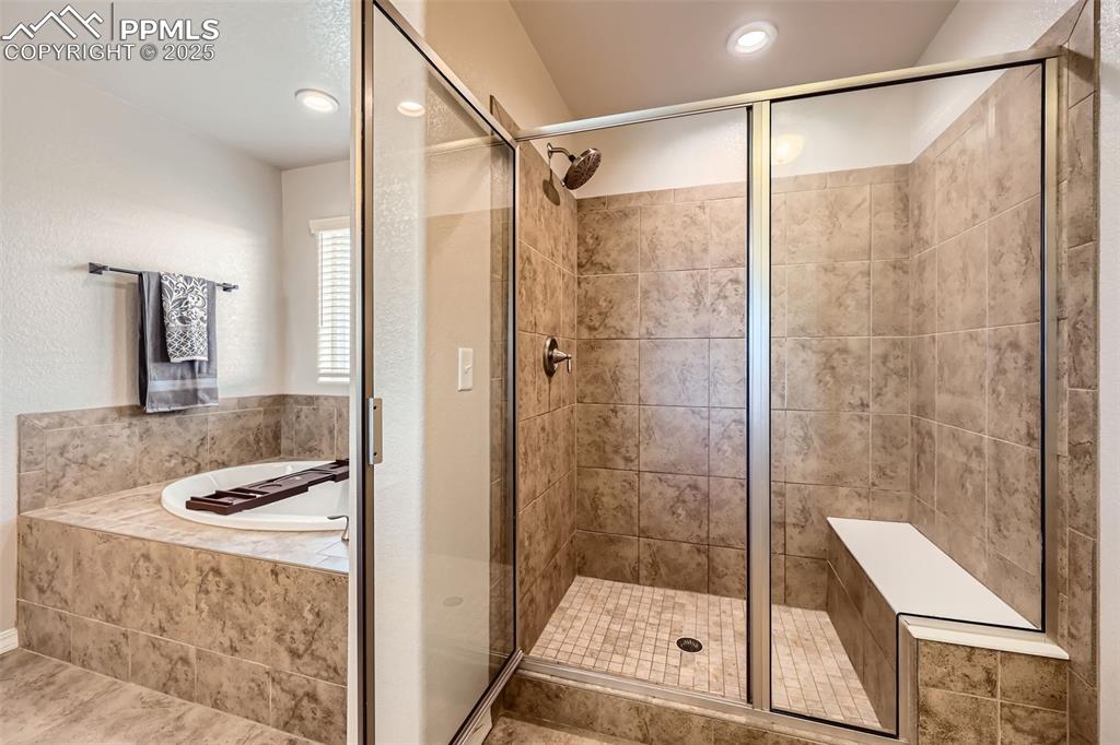 Image 17 of 29: Bathroom with a garden tub, a stall shower, and recessed lighting