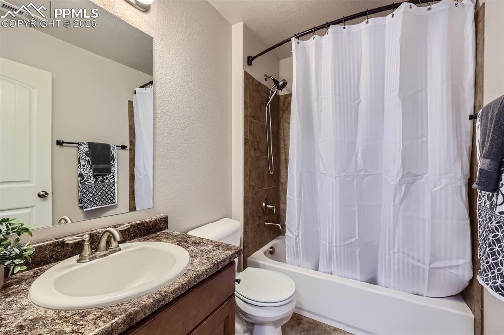 Image 21 of 29: Bathroom with toilet, vanity, shower / bathtub combination with curtain, an