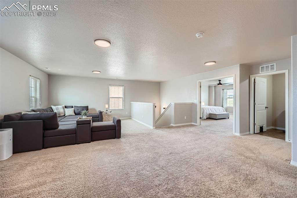 Image 25 of 29: Living room with carpet floors, baseboards, a textured ceiling, and a ceili
