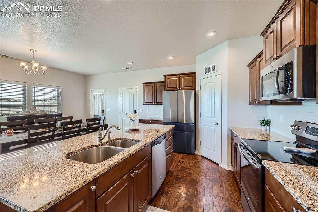 Image 8 of 29: Kitchen featuring appliances with stainless steel finishes, a sink, dark wo