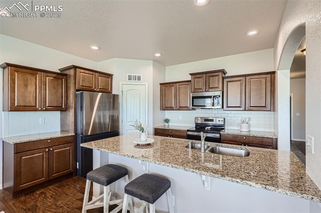 Image 9 of 29: Kitchen with appliances with stainless steel finishes, a breakfast bar area