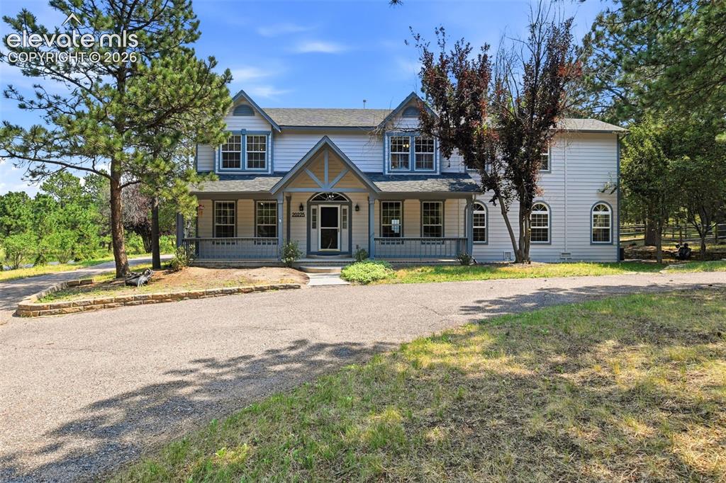Caption: Two-story residence with a covered front porch and a gabled entry