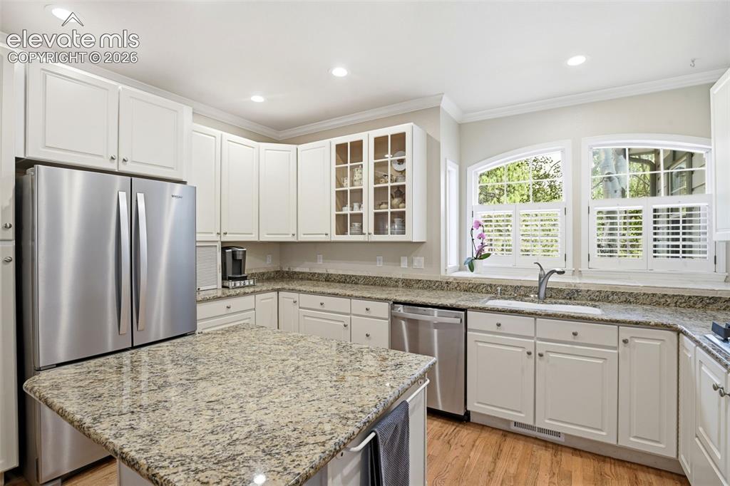 Image 3 of 44: White cabinetry with stainless steel appliances, granite countertops, cente