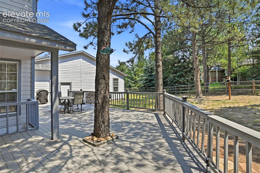 Image 42 of 44: Expansive outdoor deck with a continuous railing system, featuring mature t