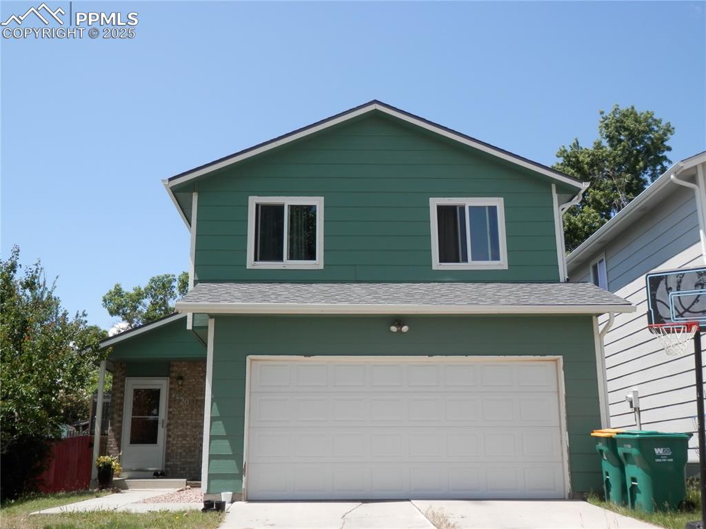 Caption: View of front of home featuring an attached garage, concrete driveway, and roof with shingles