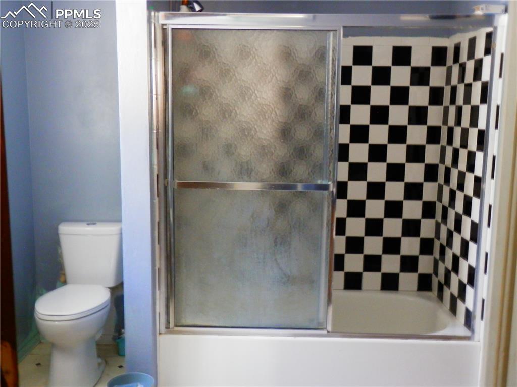 Image 20 of 29: Bathroom featuring toilet and bath / shower combo with glass door