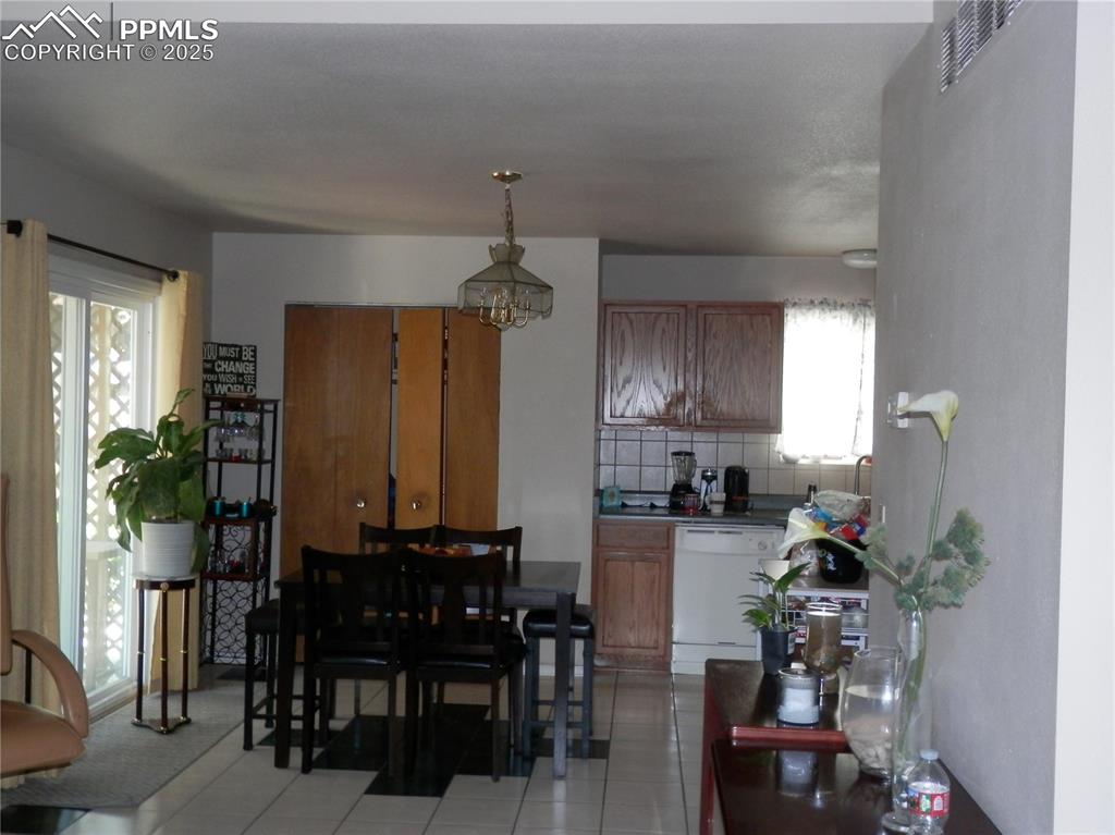 Image 8 of 29: Dining area with light tile patterned floors and a chandelier