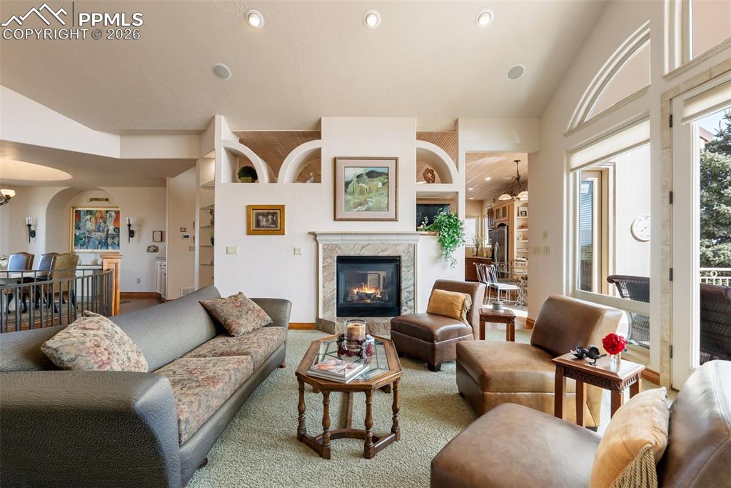 Image 7 of 50: Living room featuring built in features, lofted ceiling, a fireplace, arche