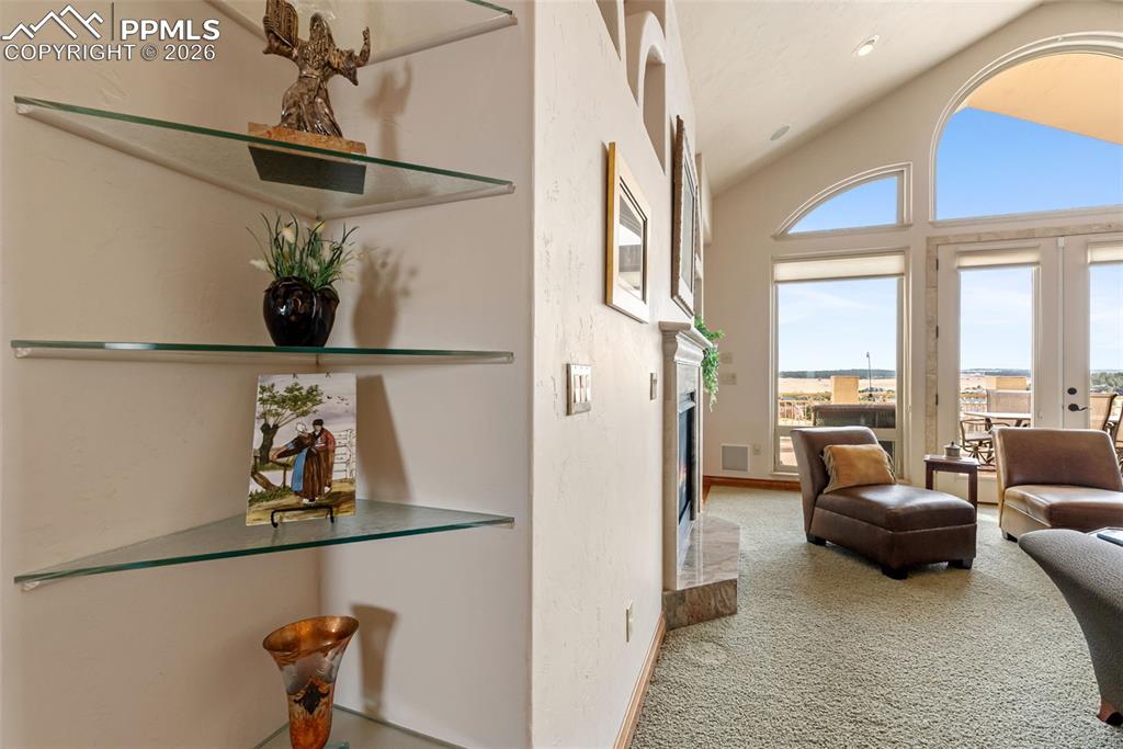 Image 9 of 50: Living area featuring a high end fireplace, carpet floors, and lofted ceili