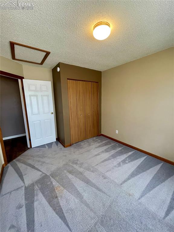Image 10 of 29: Unfurnished bedroom with a closet, a textured ceiling, and light carpet