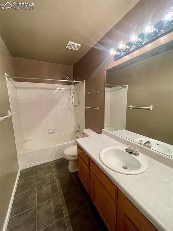 Image 12 of 29: Full bath with vanity,  shower combination, and dark tile patterned floors