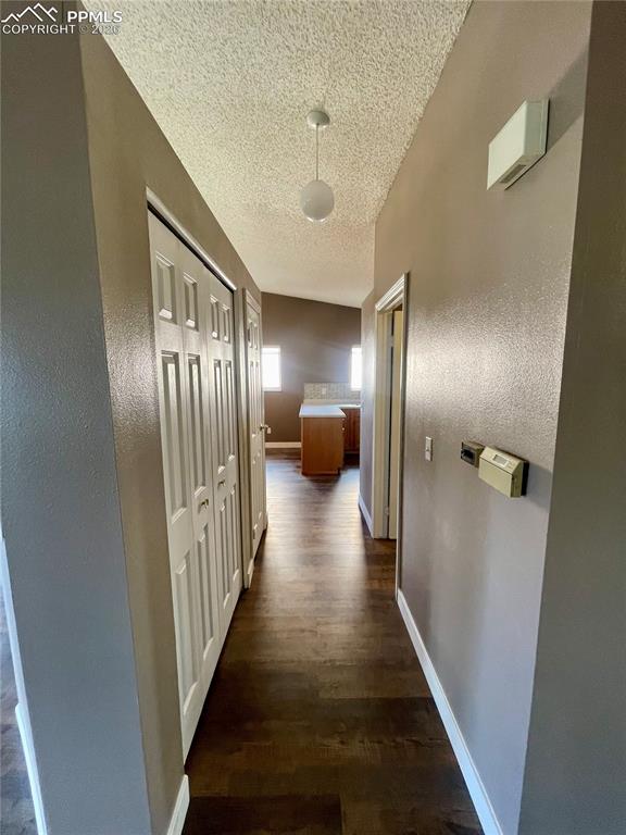 Image 13 of 29: Corridor with dark wood-type flooring and a textured ceiling