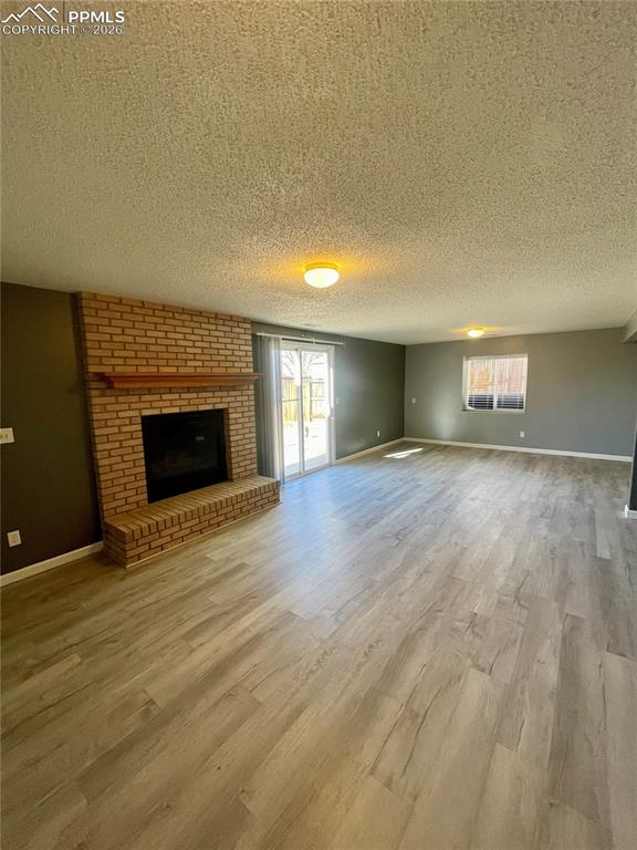 Image 19 of 29: Unfurnished living room featuring a brick fireplace, a textured ceiling, an