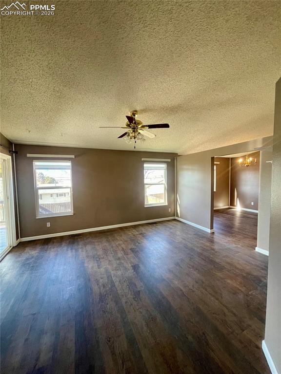 Image 2 of 29: Empty room featuring dark wood finished floors, a ceiling fan, and a textur