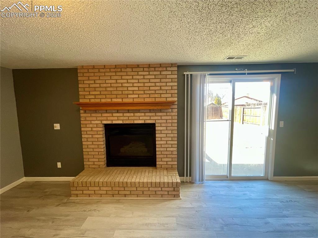 Image 20 of 29: Unfurnished living room featuring a textured ceiling, a brick fireplace, an
