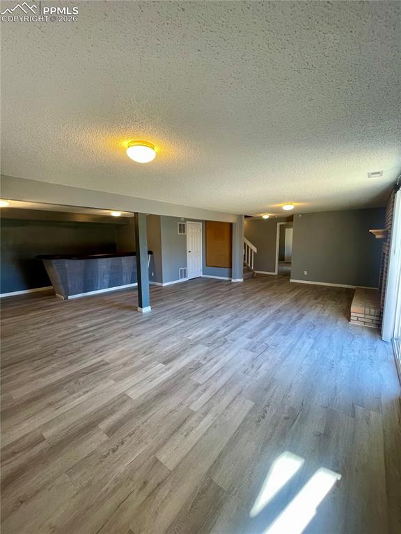 Image 22 of 29: Unfurnished living room with a textured ceiling, light wood-style floors, a