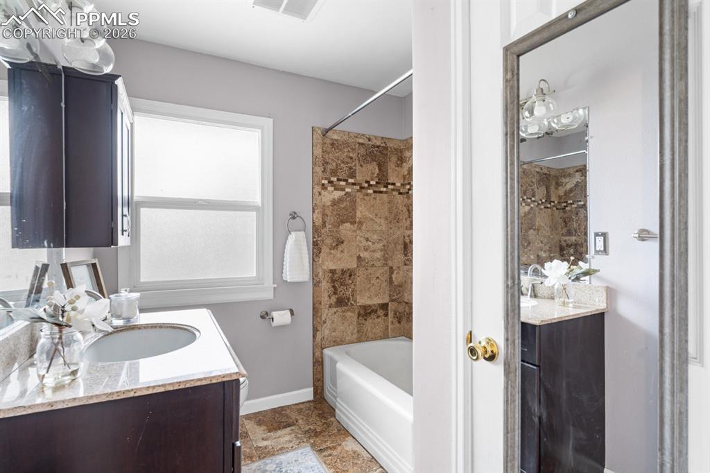 Image 15 of 32: Bathroom with travertine floors and tub surround!  Linen closet!