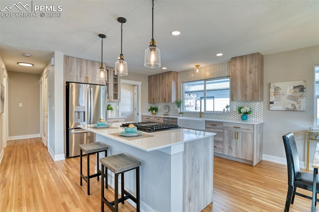 Image 12 of 30: Kitchen featuring stainless steel appliances, a breakfast bar, decorative l