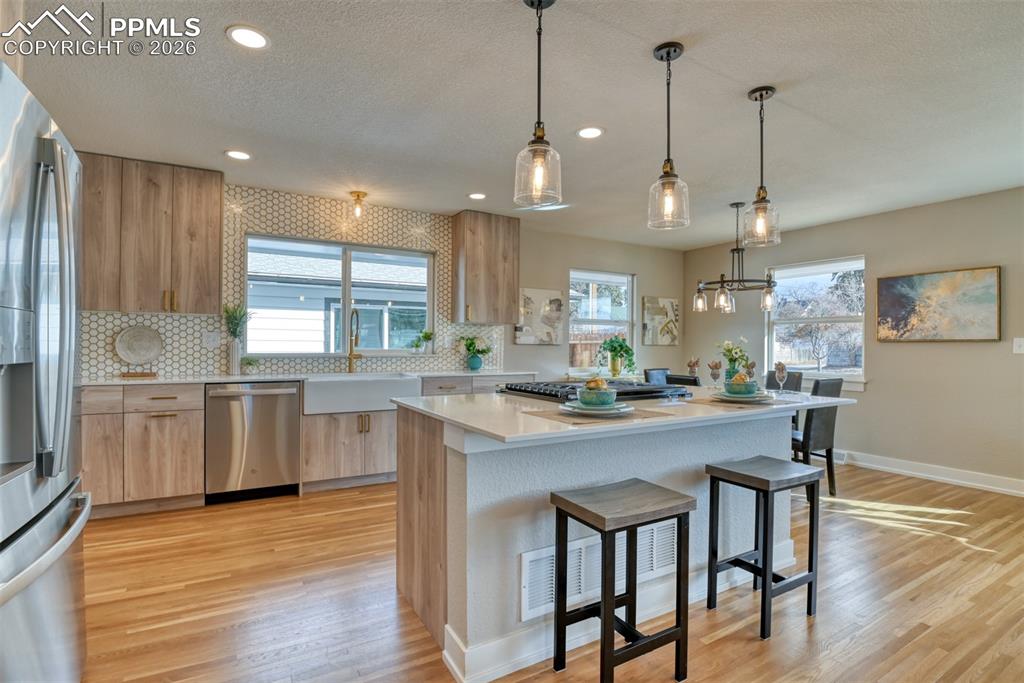 Image 13 of 35: Kitchen with light stone countertops, modern cabinets, stainless steel appl