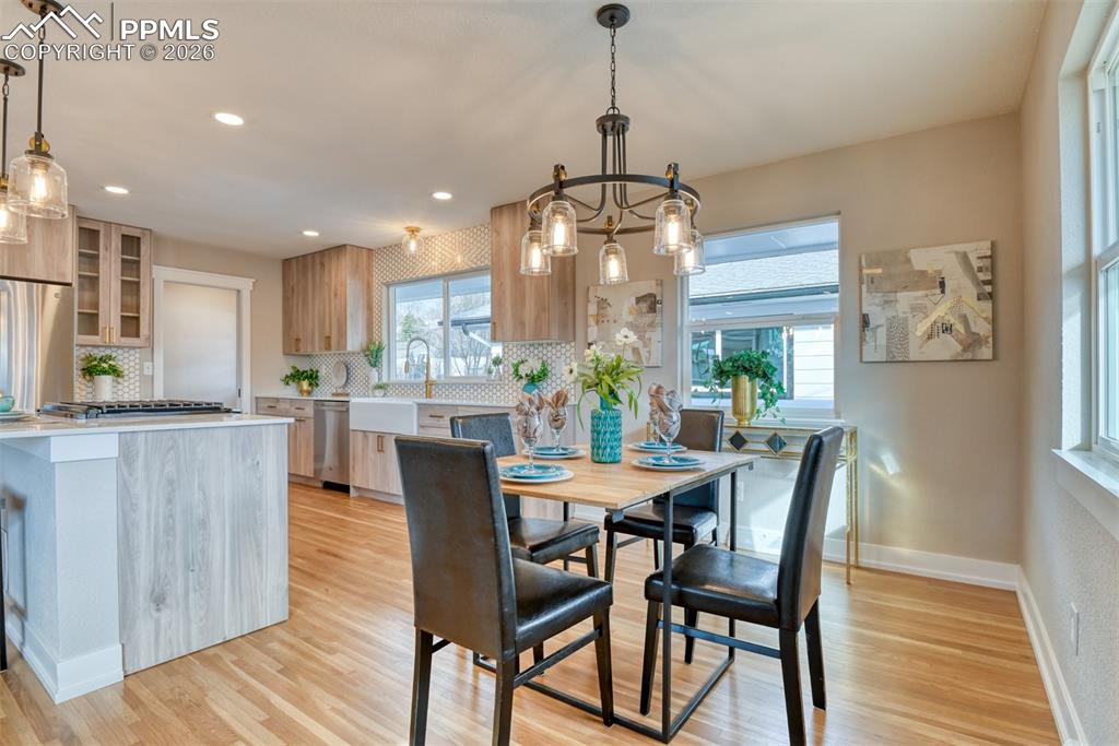Image 16 of 30: Dining room with light wood-style flooring and hanging lights