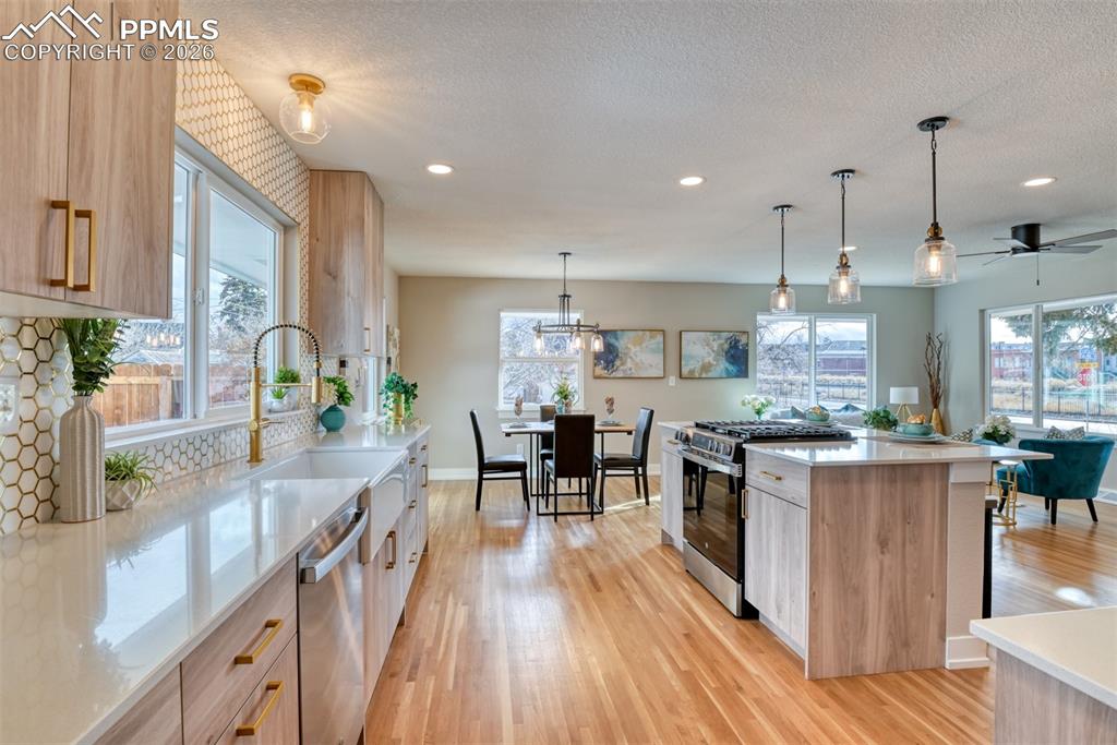 Image 16 of 35: Kitchen with stainless steel appliances, pendant lighting, light wood-style