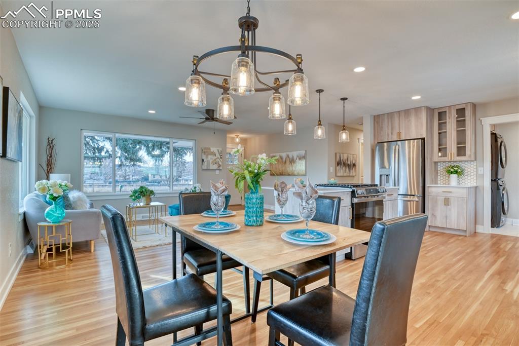 Image 17 of 35: Dining area with a chandelier, light wood finished floors, stacked washer a