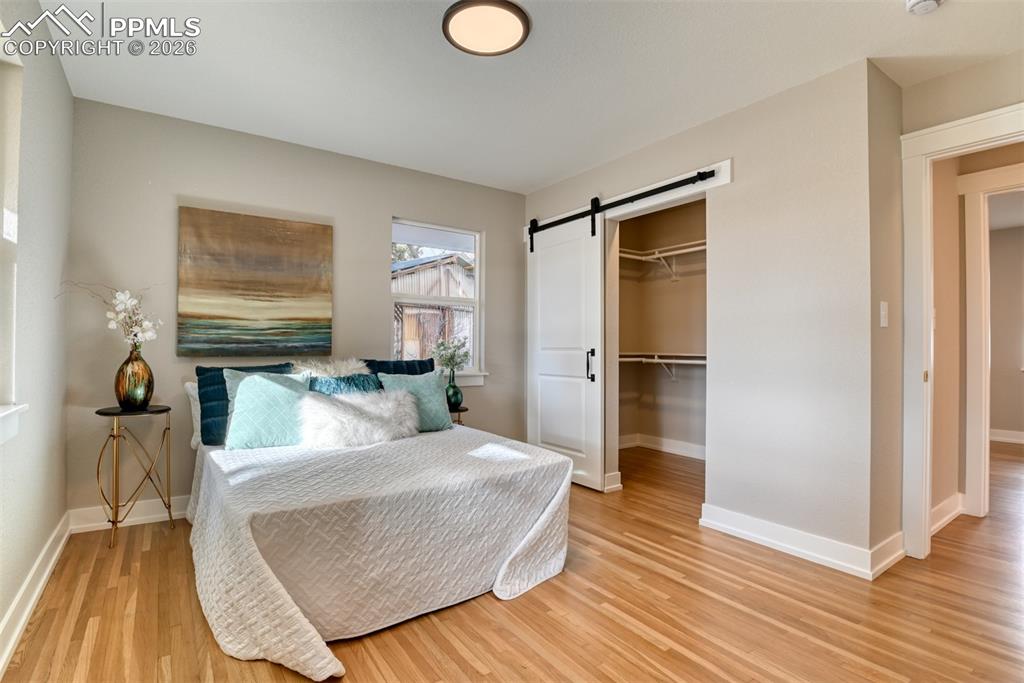 Image 18 of 30: Bedroom with a barn door, a spacious closet, and light wood finished floors