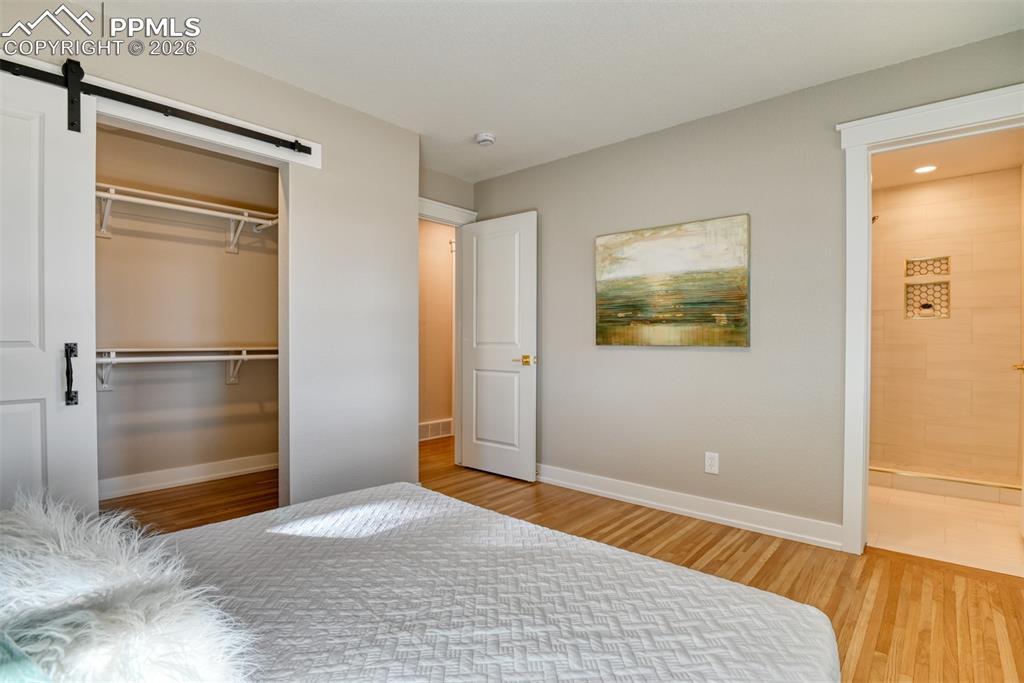 Image 21 of 35: Unfurnished bedroom featuring a barn door, light wood finished floors, and