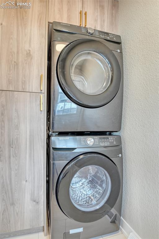 Image 28 of 35: Laundry area with a textured wall and stacked washer and dryer
