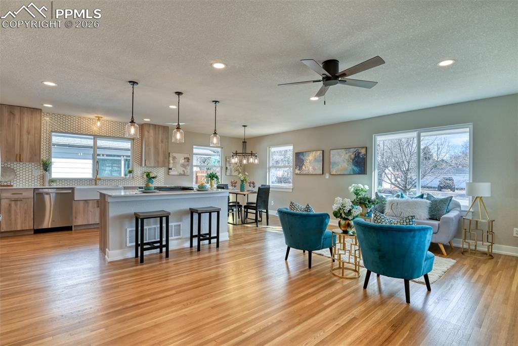 Image 9 of 30: Living room featuring light wood-type flooring, ceiling fan, a textured cei