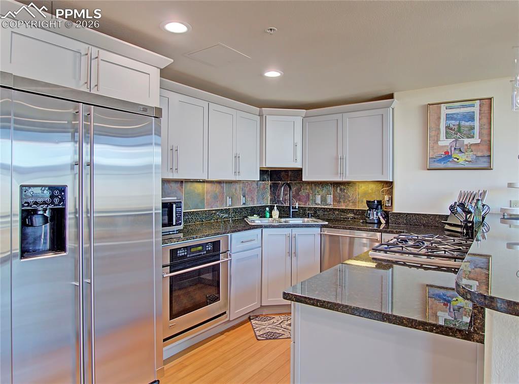 Image 14 of 20: Kitchen with stainless steel appliances, dark stone countertops, a peninsul