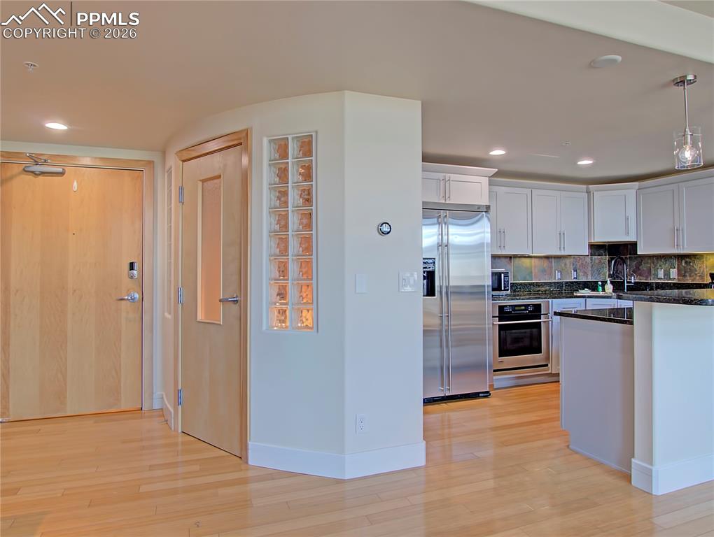 Image 6 of 20: Kitchen featuring stainless steel appliances, white cabinets, light wood fi